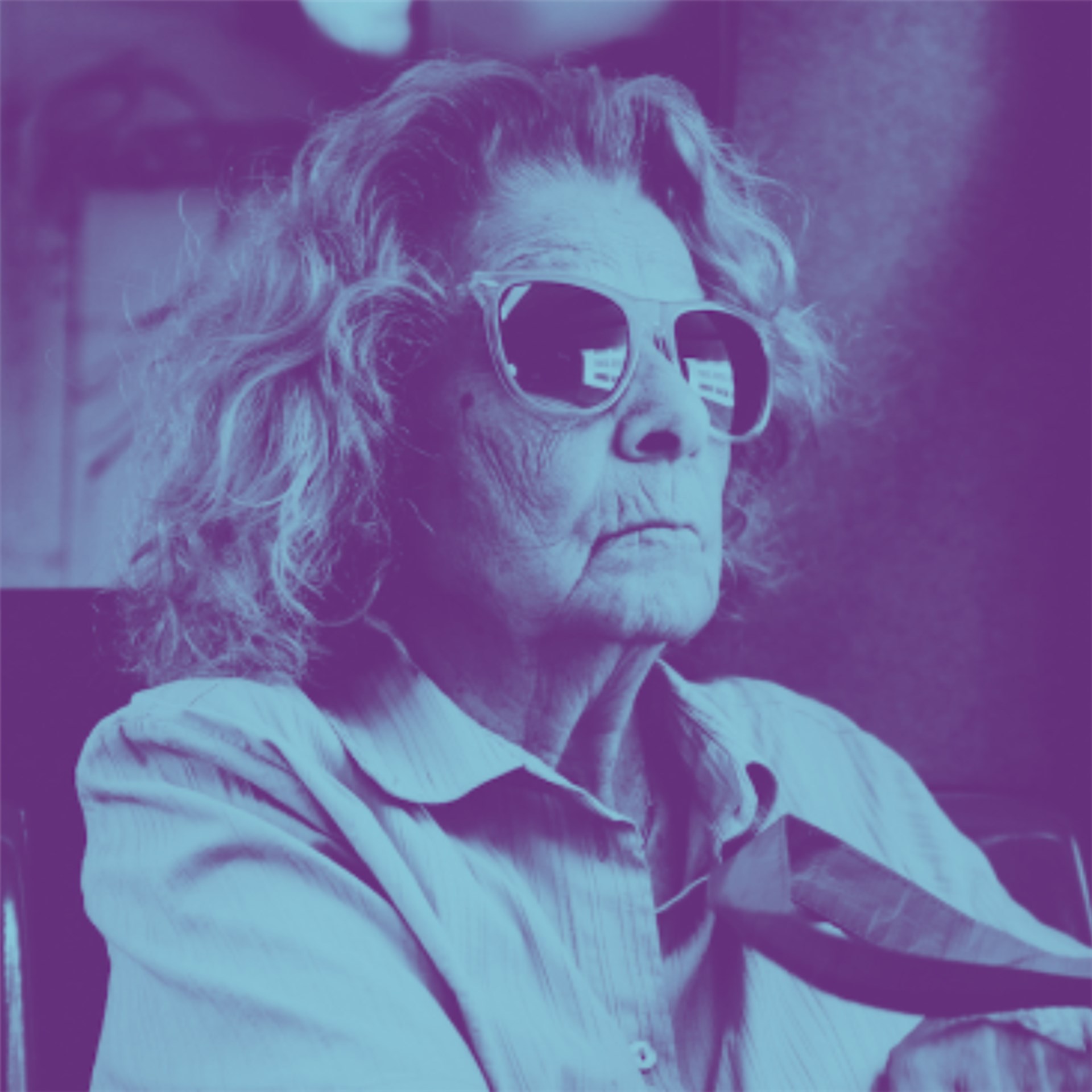 Eine alte Frau trägt eine große Sonnenbrille. Das Bild ist blau unterlegt. 